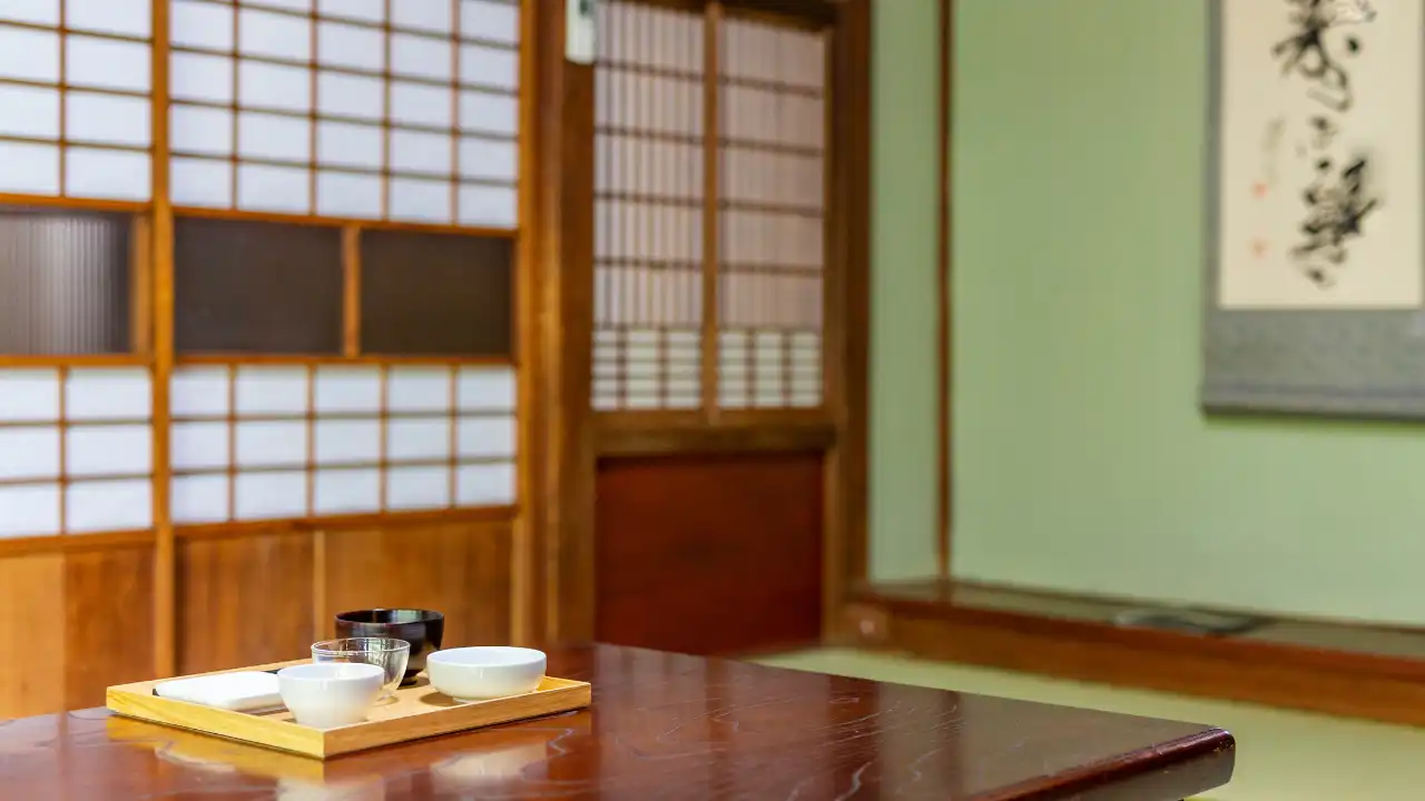 旅館の客室の背景。テーブルの上にお茶碗などの食器が置かれている部屋の風景画像