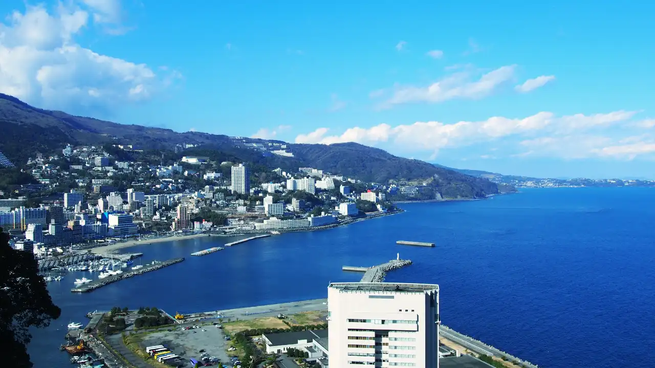 青空と青い海が広がり海沿いには沢山の建物が並び漁港乗り場のある画像