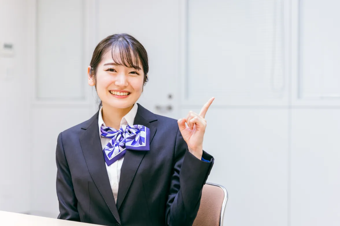 ホテルのフロントで指を指すスーツ姿の女性
