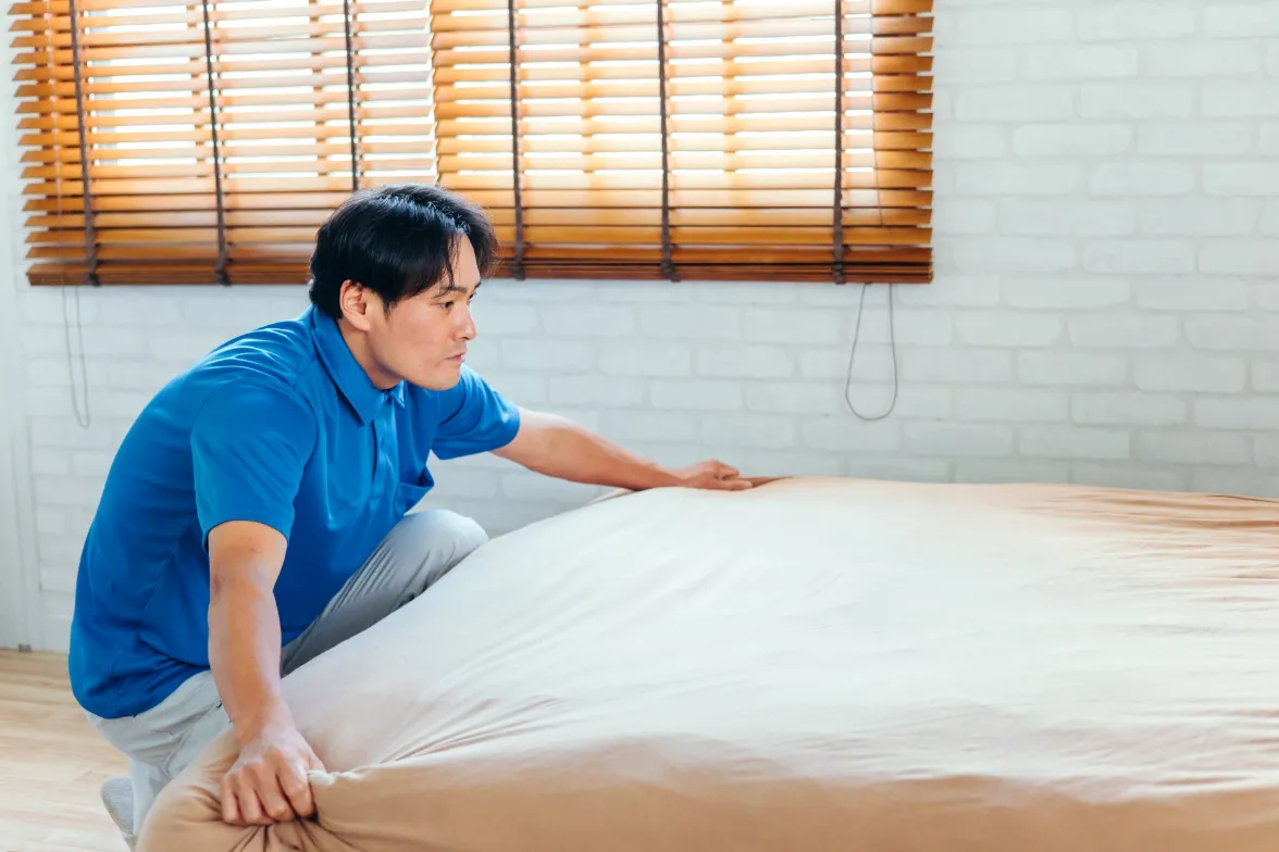 中年男性がベッドメイキングをしている